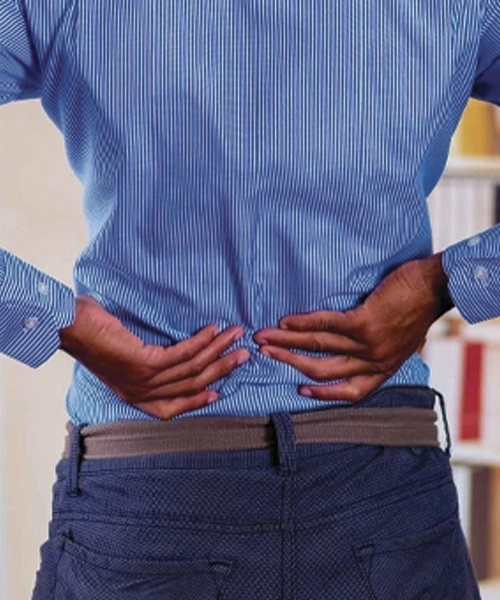 A person holding their lower back, illustrating discomfort or pain — a visual representation of lower back pain.